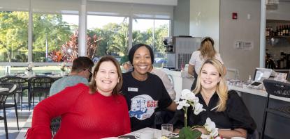 Rita Tennyson poses with two customers behind an elegant display of food