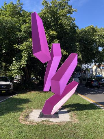 Violet, 3D blocks levitate in a patch of green grass in between two roads