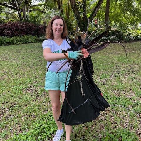 Volunteer with plant debris and a trash bag