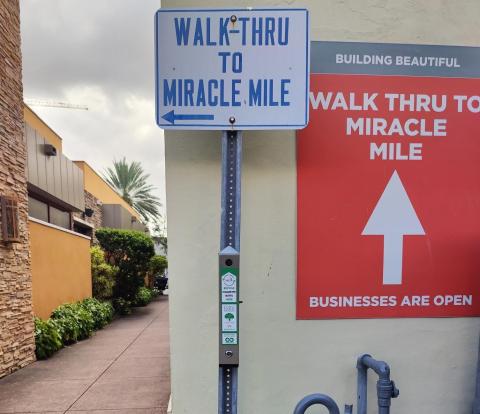 Cigarette receptacle attached to a sign that points to Miracle Mile