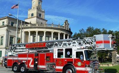 Fire truck parked in front of city hall. Blue sky sky behind city hall