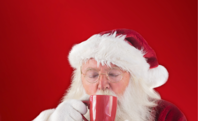 Santa drinks from a red mug in a red background