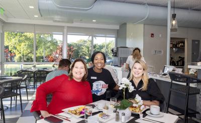 Rita Tennyson poses with two customers behind an elegant display of food