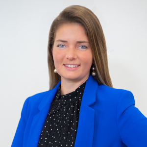 Carolina Vester wears bright blue jacket with white polka dot black shirt in front of a light gray background